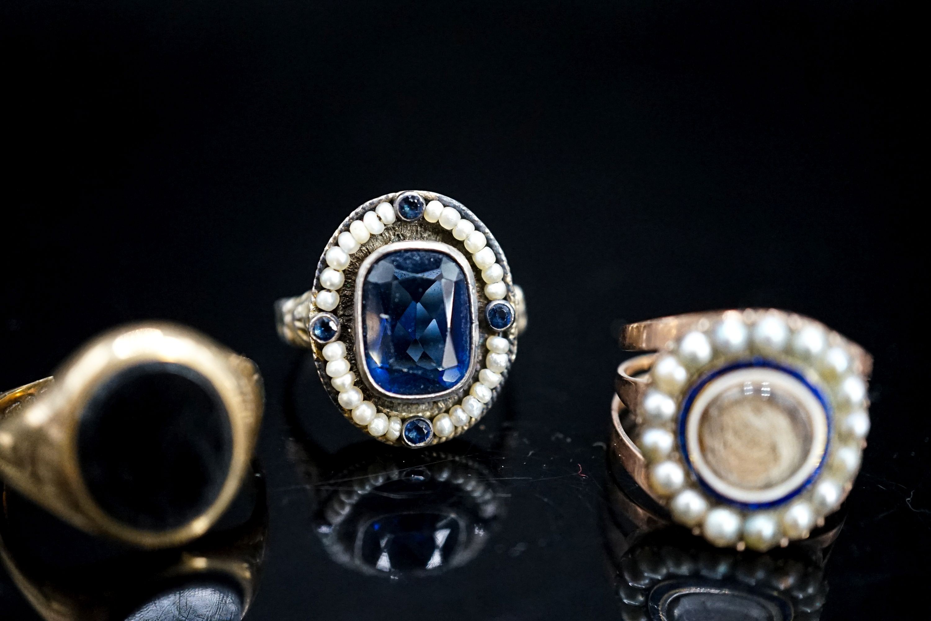 A 19th century yellow metal, two colour enamel and seed pearl set mourning ring, with hair beneath a glazed panel, size N, a 19th century Austro-Hungarian white metal and blue paste ring and a later 9ct gold signet ring(